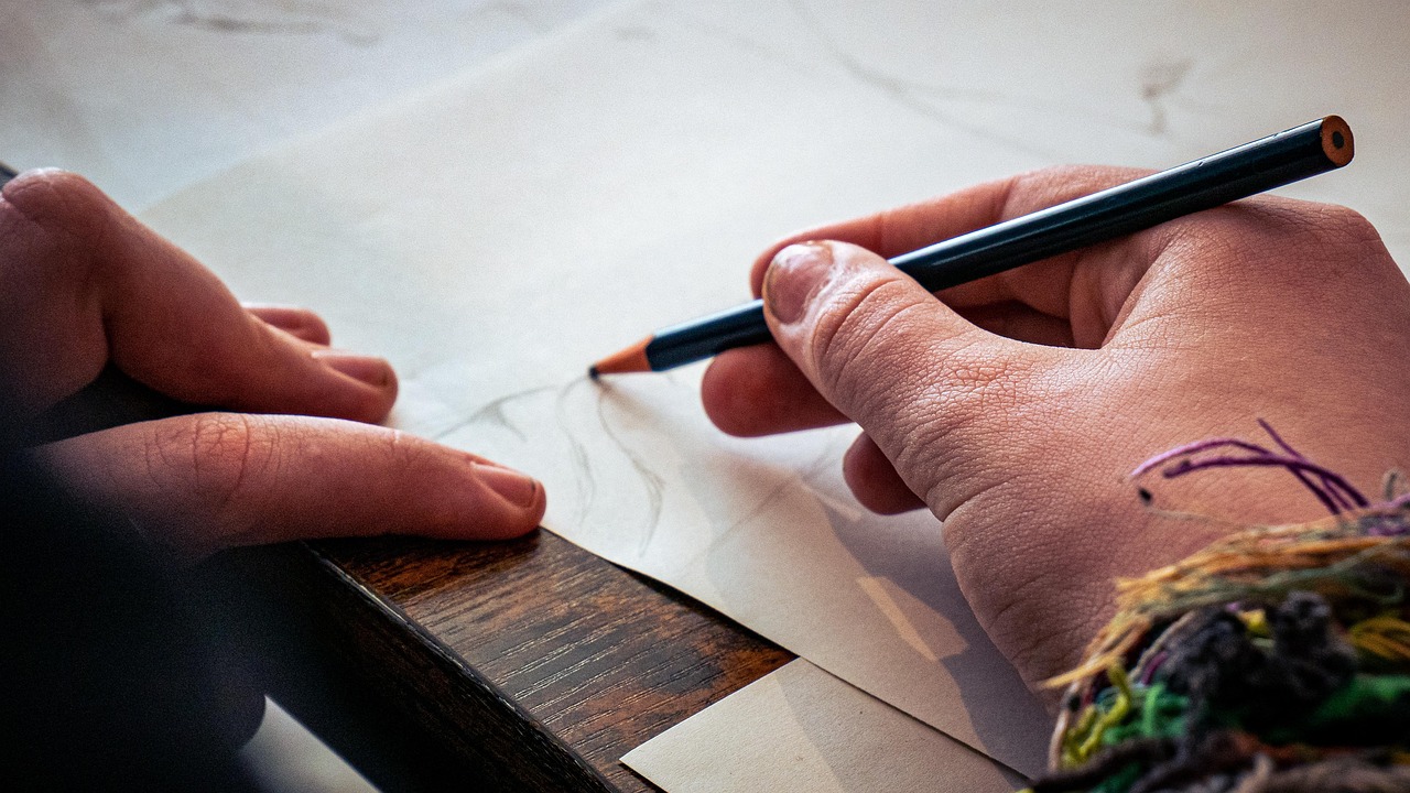 a hand sketching a drawing on paper with a black pencil