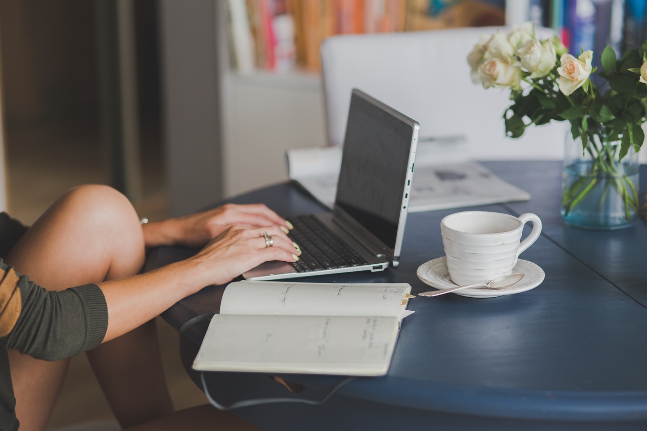 typing on laptop outdoors at a table with flowers