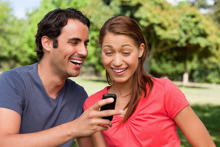 Man laughing as he shows something on his phone to his friend wh