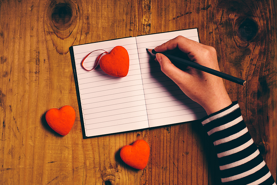 hand writing on paper with hearts scattered over it
