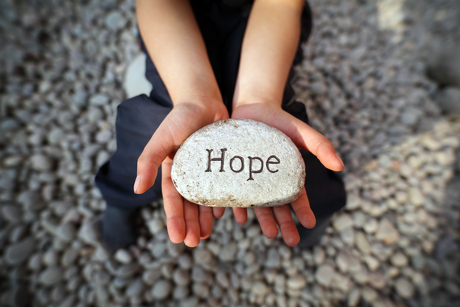 person holding a rock with the word 'hope' on it