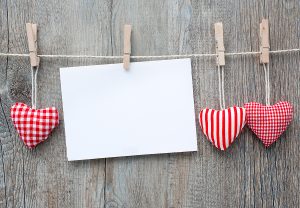 hearts and an envelope hanging on a clothes line with a wooden desk background