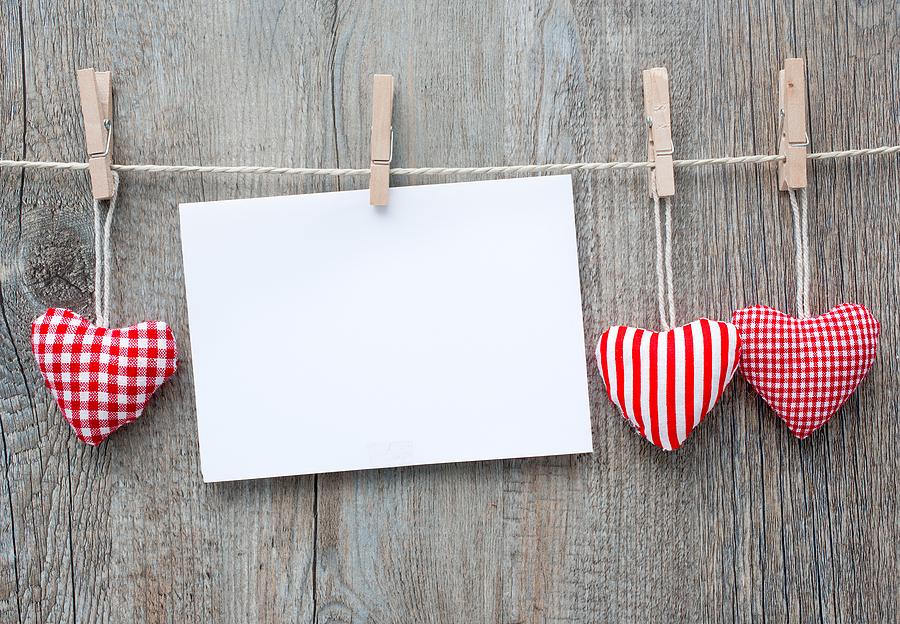 hearts and an envelope hanging on a clothes line with a wooden desk background
