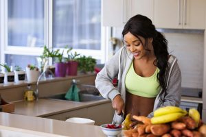 Woman in exercise attire in the kitchen cutting fruit