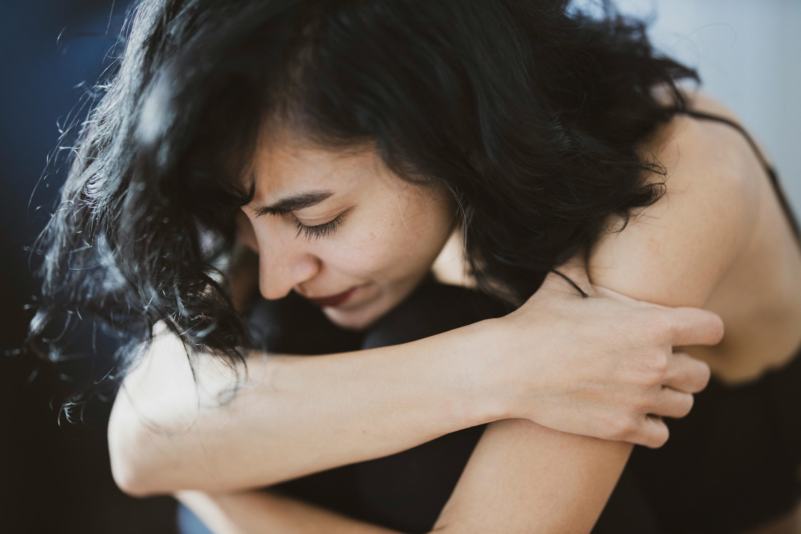 sullen woman sitting and hugging herself with both arms
