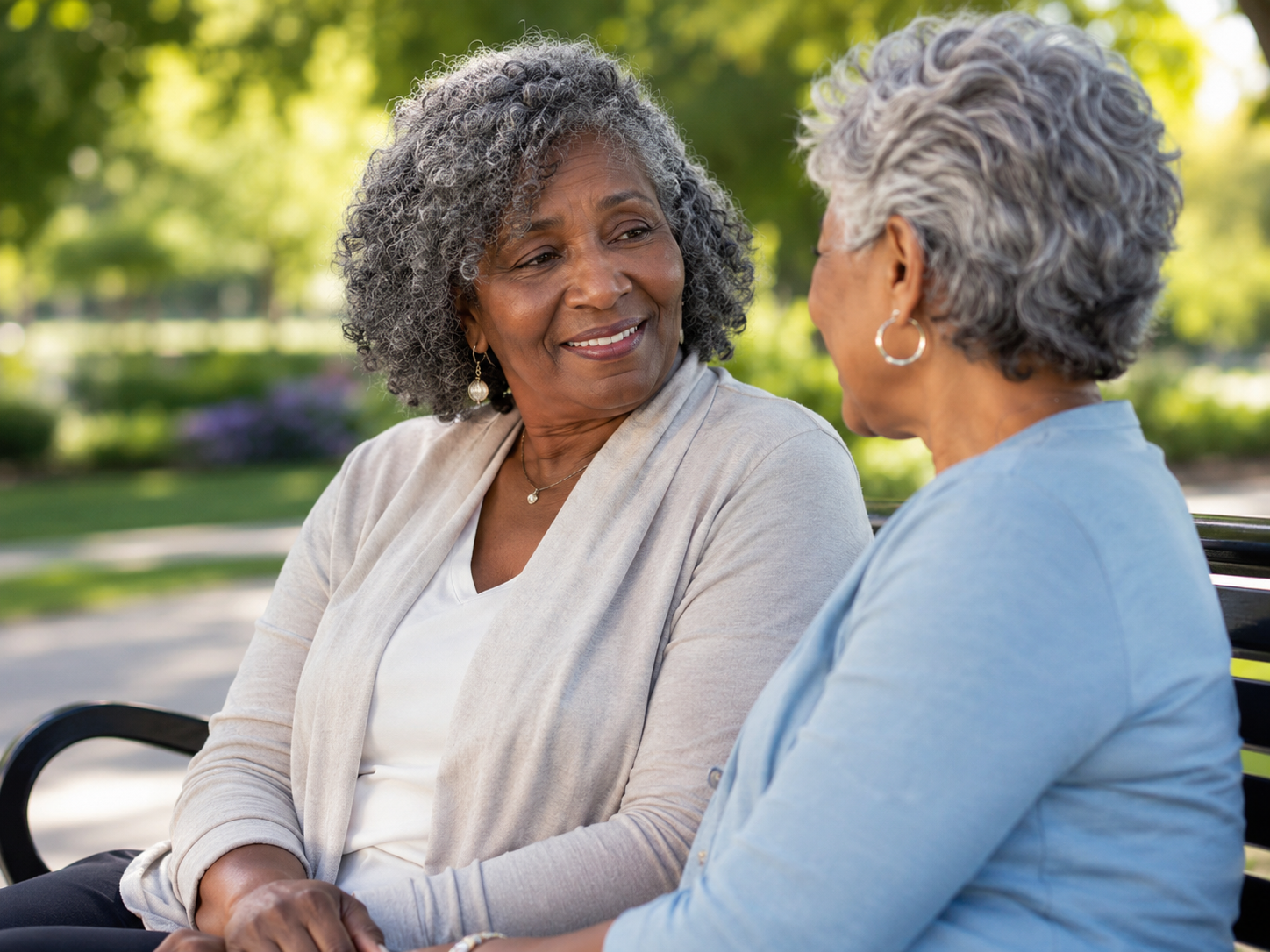 Two friends sitting together on a sunny park bench in supportive conversation, representing the importance of reaching out for help when fear feels too big to carry alone.